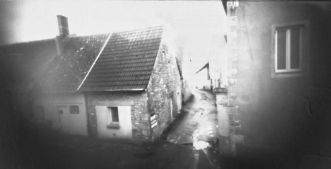foto en blanco y negro del callejón en frente de mi ventana. Se distinguen las casas a los lados del callejón, el resto es borroso.