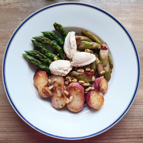 6 grüne Spargelspitzen, 4 Stücken Pfirsich, gründe Spargelstücke und 3 Nocken vo der hellen Mousse auf dem Teller dekoriert mit Pinienkernen.