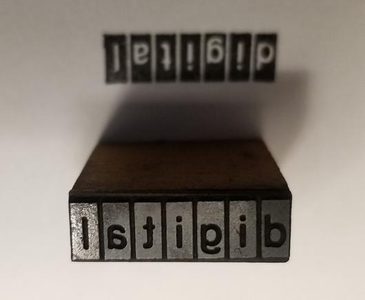A letterpress logo block for DEC, with the older 70s and 80s square "i" dot. The block is next to an impression from it to show the "positive" image.