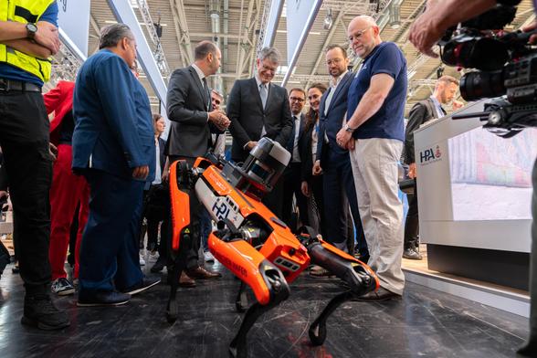 Bei seinem Messerundgang auf der transport logistic in München beobachtet Patrick Schnieder einen vierbeinigen, orangefarbenen Roboter.