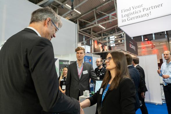 Bei seinem Messerundgang auf der transport logistic in München unterhält sich Patrick Schnieder an einem Messestand mit einer Frau.