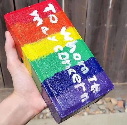 brick painted in pride colors
"to whom it may concern" is written on it