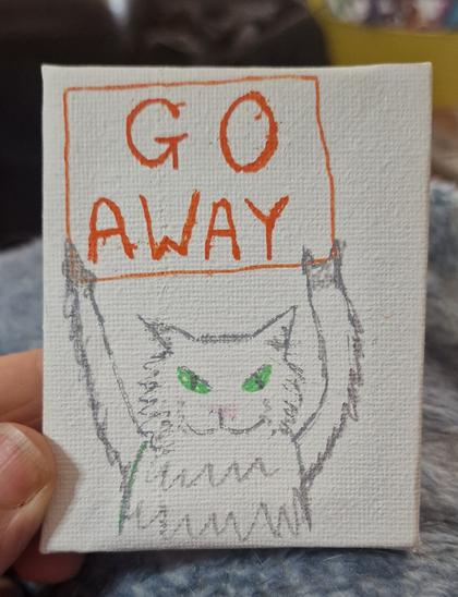 A small sketch of a grey cat in paint pen on a white canvas. The cat is holding an orange sign saying GO AWAY
