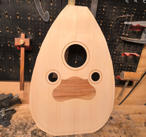 A soundboard for an oud under construction. It has a raqma (pickguard) of apple wood and inlaid rings around the soundholes of sapele (which will match the body).