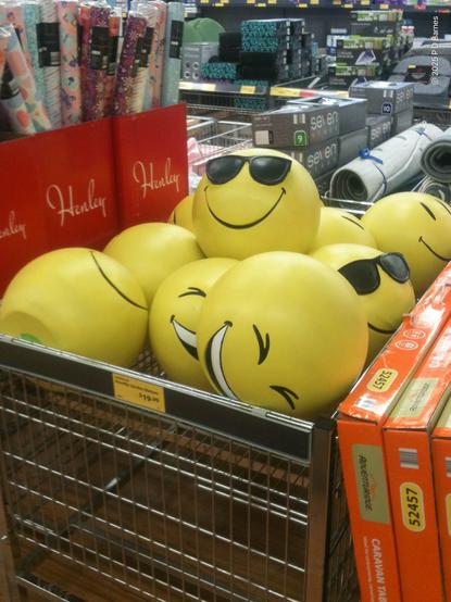A centre aisle bin with yellow bouncy balls with laughing and sunglasses emojis faces, lying, laughing and smiling