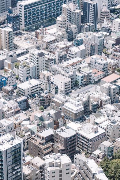 Aerial view of a dense urban area in Tokyo, Japan, showcasing numerous residential and commercial buildings with varying architectural designs