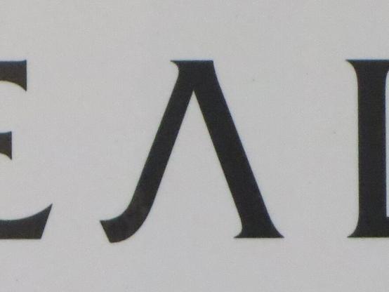 Чёрная буква Л с засечками на белом фоне, часть логотипа. // Black letter L with serifs on a white background, part of the logotype.