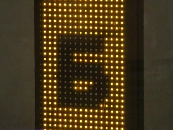 Чёрная буква Б на вертикальном светодиодном табло, часть минималистичного оформления витрины. // Black letter B on a vertical LED board, part of the minimalist design of the shop window.