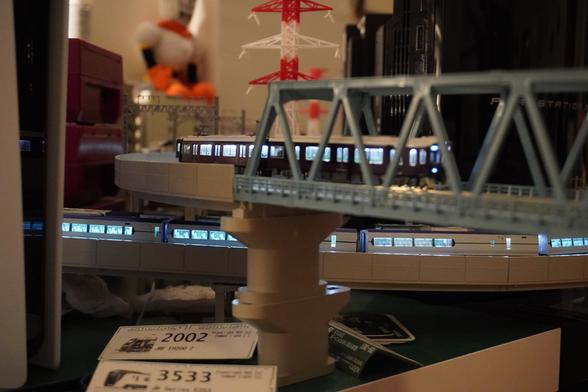 Train entering a bridge after exiting a valley made out of high rises. Another train passing underneath it