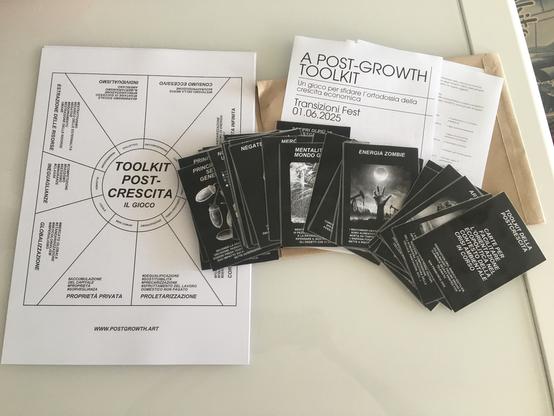 Picture shows the post-growth toolkit, including a game board, black cards with key post-growth concepts, and instructions