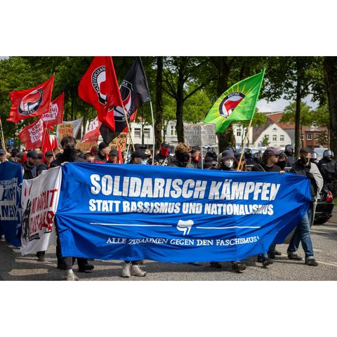 Frontblock der antifaschistischen Demonstration. Auf dem Frontbanner steht solidarisch Kämpfen statt Rassismus und Nationalismus. Alle zusammen gegen den Faschismus. In der Demo sind mehrere Antifa Fahnen zu sehen