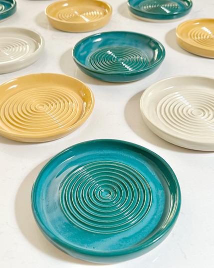 Blue, yellow, and off white ceramics plates with grooves in the center.