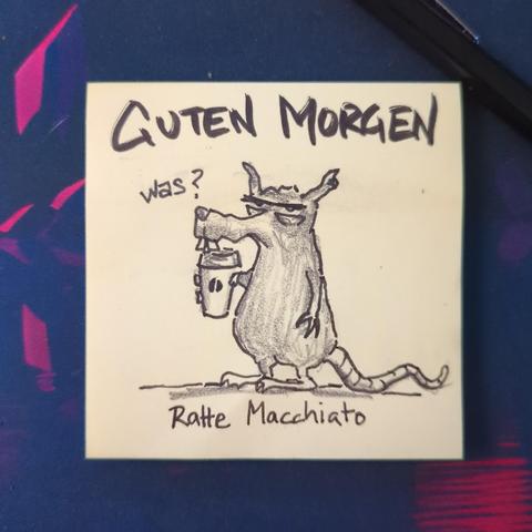 Auf einer gelben Haftnotiz steht "guten Morgen".
Darunter ist eine genervt dreinblickende Ratte mit to-go Kaffebecher zu sehen.
Es ist ein Ratte Macchiato.