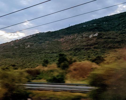 La colline de la grotte Mandrin vue depuis le TGV. Malgré la déformation due à la vitesse, on distingue clairement l'amas de rochers qui signale la grotte.