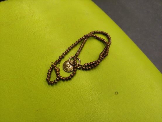 A beautiful brown bracelet/necklace with a gold charm.