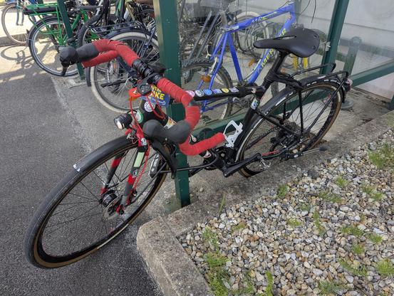 mon vélo accroché à la structure d'un abri vélo à pince roues.