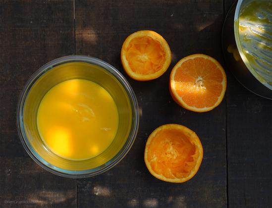 Glas mit Orangencreme auf dunklem Hintergrund. Orangenschalen ausgepresst. Ein Topf angeschnitten mit Resten der Creme.