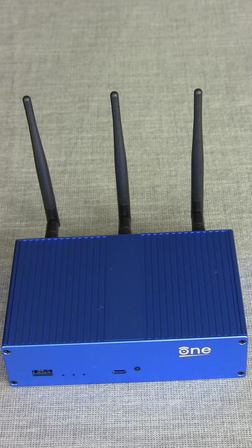 OpenWRT One - blaues Gehäuse mit drei Antennen auf Tischdecke
