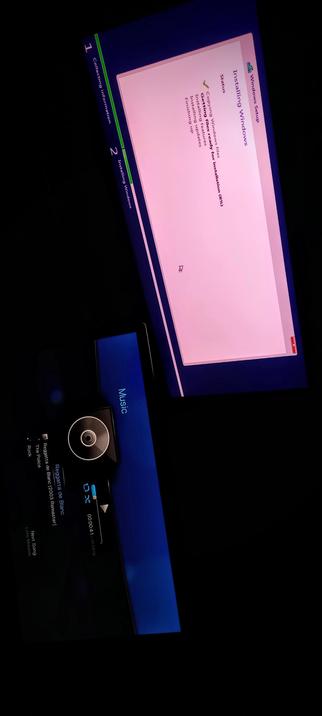 The photograph composed in total freedom & darkness shows an IPS LED panel  displaying the Windows Setup process, with a progress bar indicating "8%" completion. The screen is titled "Installing Windows" and lists several steps, including "Getting Windows files ready," "Installing features," and "Finishing up." The background of the screen is pink, and the Windows logo is visible in the top right corner. Below the screen, there is a music player interface showing a CD player with a disc inserted, displaying the song "Reggatton de Blanc" by The Police from the album "Reggatta de Blanc (2003 Remaster)." The music player is labeled "Music" and shows the current time as "00:04:41" with a progress bar indicating the song's duration. The overall image is set against a dark background, emphasizing the illuminated screens.

 Ovis2-8B

🌱 Energy used: 0.211 Wh