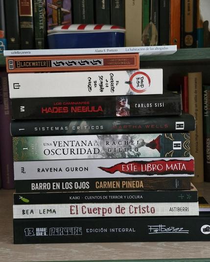 Fotografía donde se ven una pila de libros delante de una estantería con más libros.
Los libros de la pila de arriba a bajos son los siguientes:
"La habitación de las ahogadas" de Alana S. Portero
"Blackwater II. El dique" de Michael McDowell
"El guerrero a la sombra del cerezo" de David B. Gil
"Los caminantes. Hades nebula" de Carlos Sisí
"Sistemas críticos" de Martha Wells
"Una ventana a la oscuridad" de Rachel Gillig
"Este libro mata" de Ravena Guron
"Barro en los ojos" de Carmen Pineda
"Kaiki. Cuentos de terror y locura"
"El Cuerpo de Cristo" de Bea Lema
"13 Rue del Percebe. Edición integral" de Francisco Ibáñez