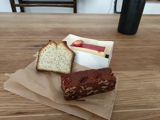 Une part de cake au citron et au pavot, une part de cheesecake à la fraise et une part de brownie sur une table en bois
