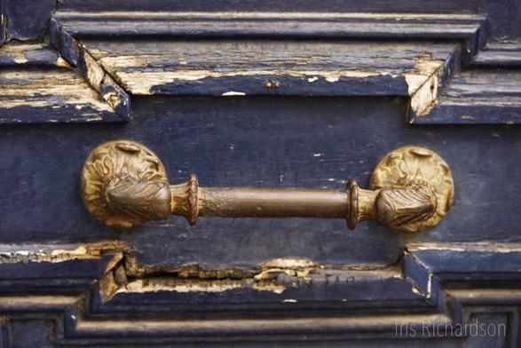 Old brass door handle on a blue weathered wooden door macro photograph