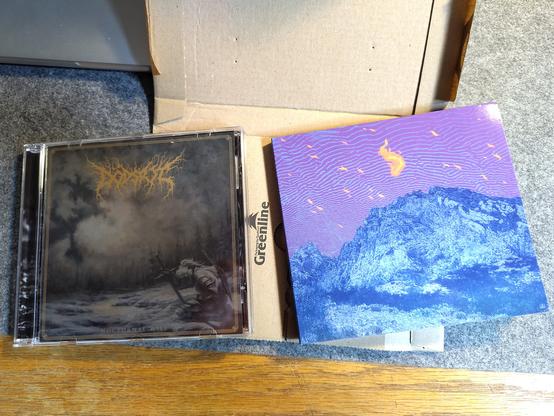 Two CD albums lying on top of a small cardboard package.