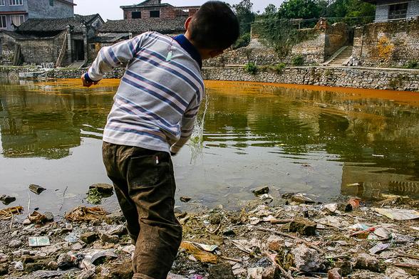 Un enfant de dos joue avec une pierre et s'applique à faire un ricochet.

Vincent Dufrène Photographies, Chine 2006