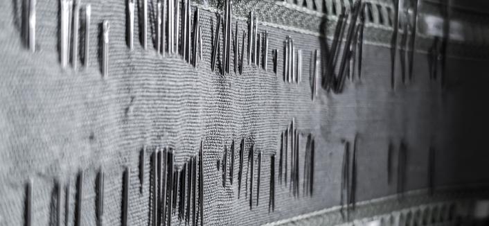 La photo présentée horizontalement propose un paysage d aiguilles de couture épinglées sur un joli tissu, avec une lumière rasante. Les aiguilles forme comme un paysage de collines acérées.