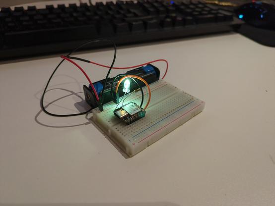 A small breadboard with a small ESP32C3 microcontroller attached to it. Instead of a USB-C cable a lithium battery is attached with two cables. On The breadboard there is also a blinking LED and a resistor for the LED.

The microcontroller is running the ESP32 blinking example. It's just a picture so you can not see it blinking but at the moment I took the picture the LED was turned on.