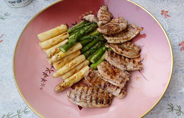 Weißer und grüner Spargel und Entenbrustfilet in Scheiben gebraten auf Gußeisenpfanne - serviert auf einem großen Teller