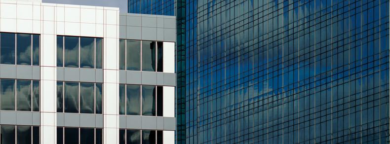 Walls of two buildings (a grey and white one on the left, a blue glass one on the right) appear to be meeting, and perhaps even be butted together at right angles, near the middle of the frame.  This is of course a visual illusion aided by the spatial compression of a long lens.