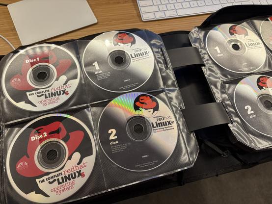 Photo of a CD binder, containing retail install CDs of Red Hat Linux 5, 6.1, 6.2, and 7.1.