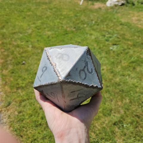 a large D20 made of galvenized metal, welded and bent pieces. It is dangerously large, heavy, and would pose ill danger if thrown above head.