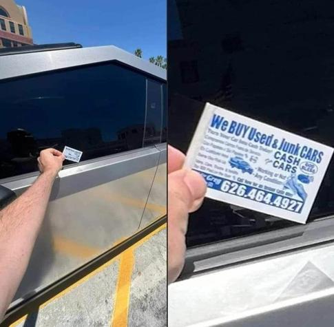 A person placing a “WE BUY USED & JUNK CARS” calling card on a Cybertruck window.