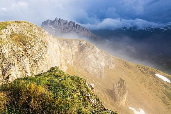 Clouds over the Greater Caucasus Range, along with fog and atmospheric mist. The landscape represents geological features from different geological epochs: Triassic, Jurassic, and the Oligocene. View from Mount Asbestnaya, Republic of Adygea, Caucasus Mountains.