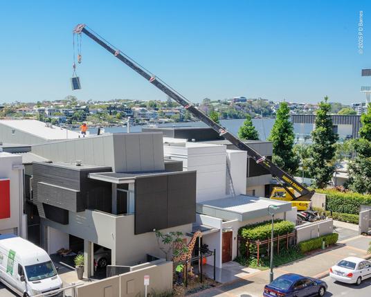 A wacky street scene. The small enclosed garden of #37 features a full-sized yellow giraffe, but it's totally upstaged by a huge yellow extensible travelling crane next door, extending over two rooftops to lower some arcane equipment.