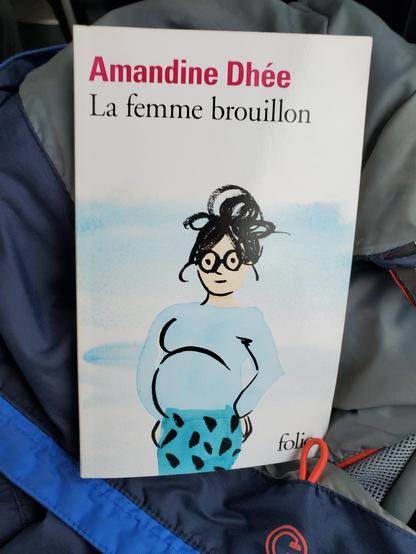 Couverture de l édition poche du livre la femme brouillon d Amandine Dhée avec un dessin de femme, enceinte avec un peu comme un sourire et des lunettes (dessin : Marguerite Courtieu)