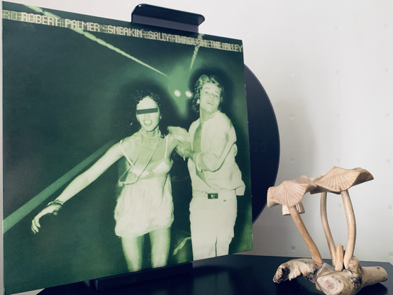 Album cover is of Robert Palmer escorting a woman (Sally we’ll presume and hopefully of her own accord) through an alleyway. It’s a two-tone green and white photo.