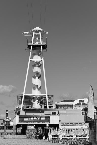 Monochrome photo of a 30 metre tower with spiral staircase to a platform where two lines  provide the longest zipwire rides on the south coast. Established 2017 at Dalton's Bastion, Madeira Drive, City of Brighton & Hove.