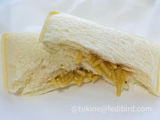 半分にカットされた『ランチパック 塩焼きそば』。ふんわりした白いパンの中に、塩焼きそばの麺と具材が見える。