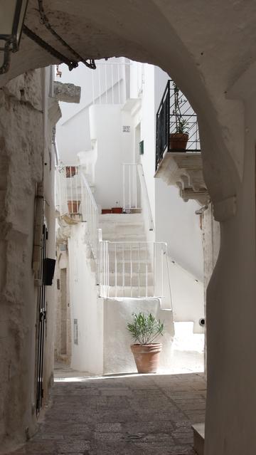 A covered alleyway, leading to a bright, white staircase.