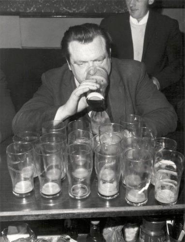 black and white photos. A man, eyes heavy, sits in front of 17 empty pint glasses, the 18th raised to his mouth. He looks smashed.