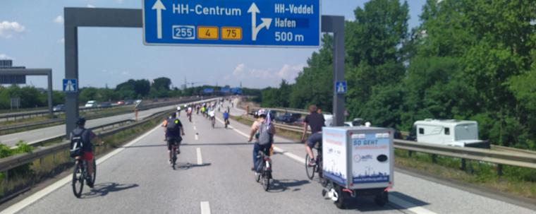 Autobahn 255 mit Fahrrädern auf der Fahrbahn. Oben eine blaue Schilderbrücke mit dem Zielort Hamburg-Centrum und der Abfahrt nach Veddel.