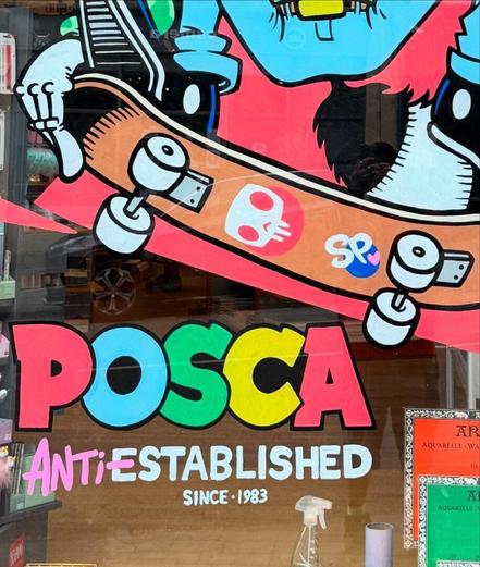 A colorful window mural features a skateboard with stickers and the words "POSCA Anti-Established Since 1983" in bold, multi-colored letters. Art supplies are visible inside the store.