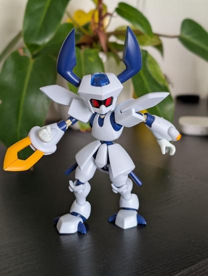 Close-up of a newly built KWG00-M Rokusho Medabot model kit, featuring its signature white and blue armor and yellow weapon.