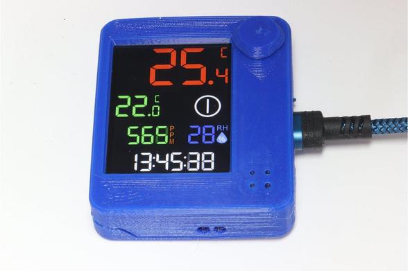 A digital display device showing temperature (25.4°C and 22°C), air quality (568 PPM), humidity (28%), and time (13:45:38). The device is housed in a blue 3D-printed case.