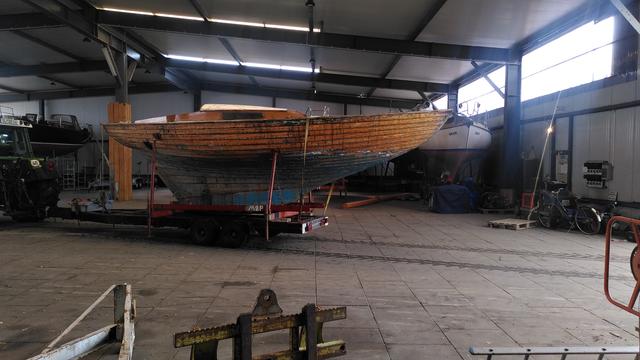 Holz-Folkeboot auf einem Bock in einer Bootshalle, von Steuerbord. Rumpf ist aufs Holz abgezogen