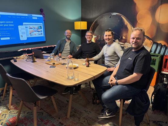 Bild vom letzten Nextcloud User Group Meetup, Teilnehmer sitzen in unserem Sitzungszimmer um einen Tisch herum und lachen in die Kamera.