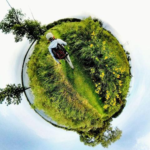 One of a series of photographs in which two people are pictured hiking, biking, and kayaking throughout a beautiful and verdant state park in central Minnesota under cloudy blue late-summer skies.